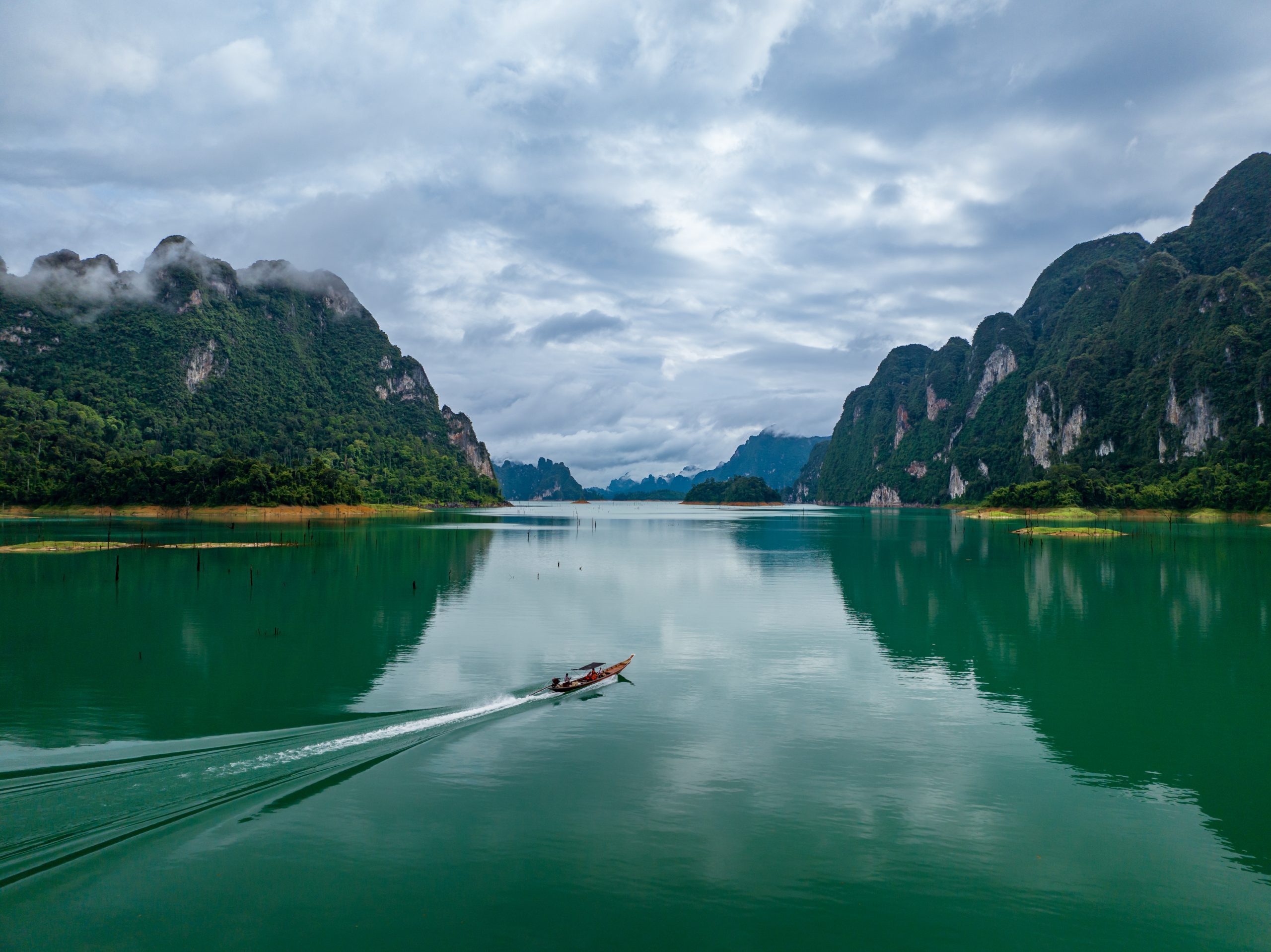 Aerial drone view of tourist boat on the lake of tropical Mountain peak , Khao Sok National Park, Thailand